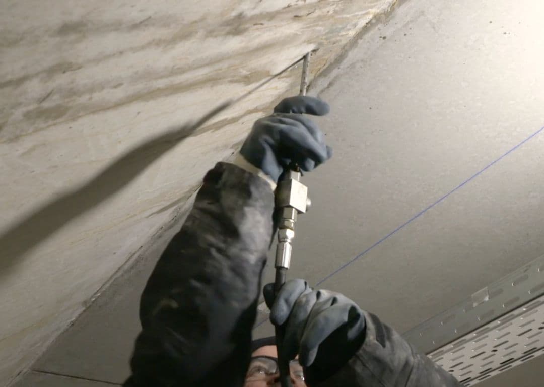 Een vakman van Kitfix injecteert een scheur in een betonnen plafond